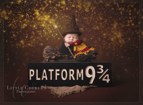 newborn baby in witches hat with harry potter scarf and wand with platform 9 3/4 sign and magic little cherubs photography cambridge huntingdon peterborough ely