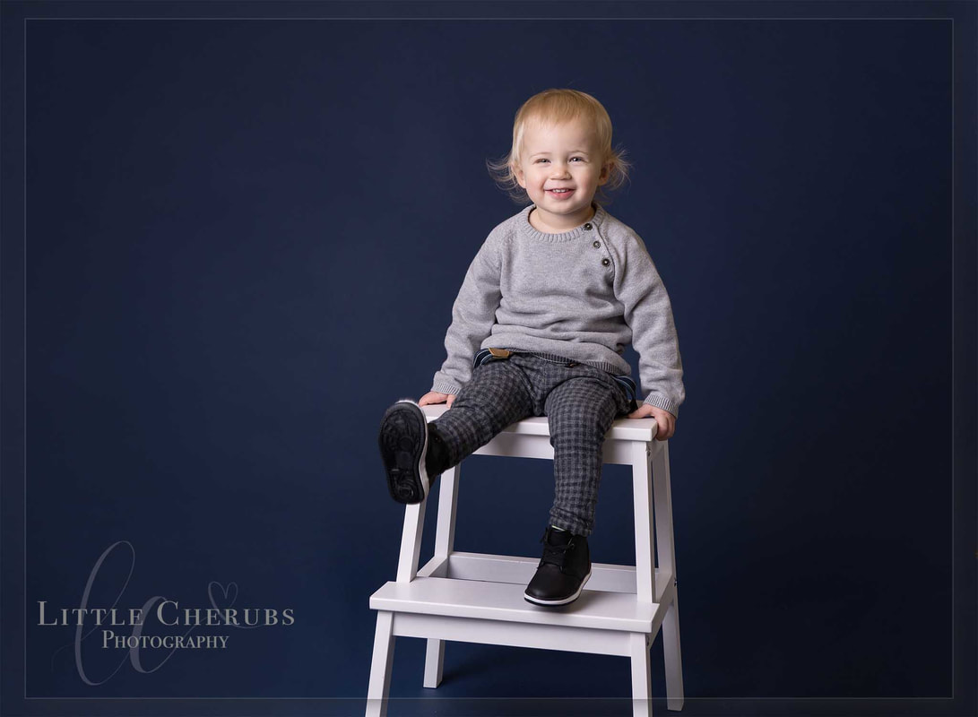 Toddler boy sitting on white steps on navy backdrop march peterborough family photographer